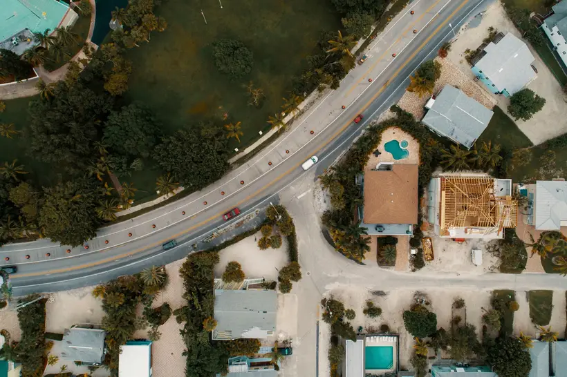 Drone view of houses, pools and a curving road