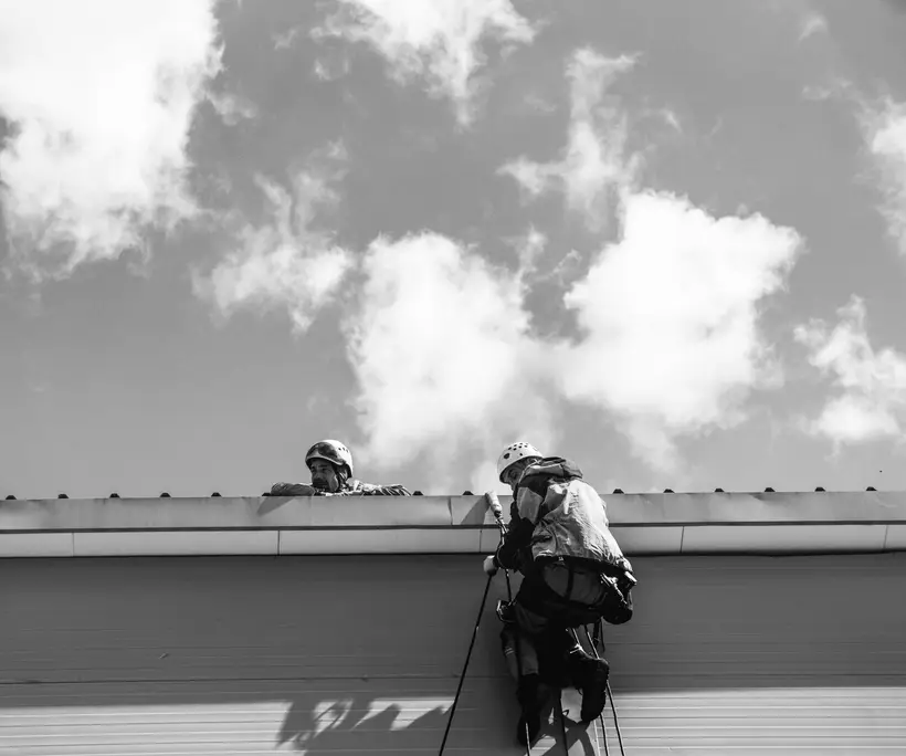 Two workers checking a roof edge