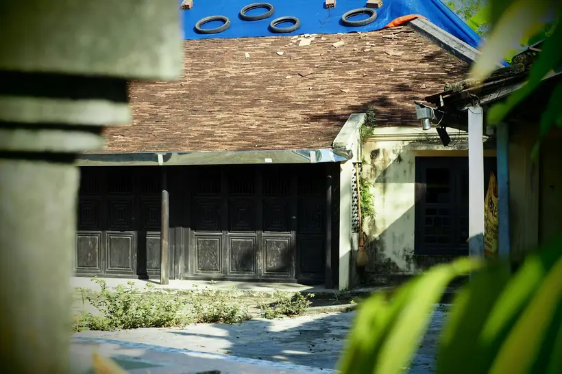 Blue tarp held down with tires on a tiled roof
